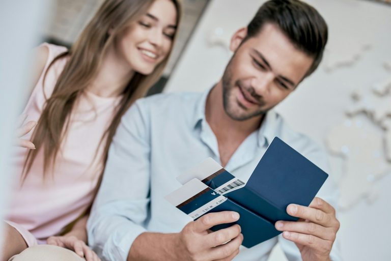 Young man smiling and reviwing tickets, passport with visa
